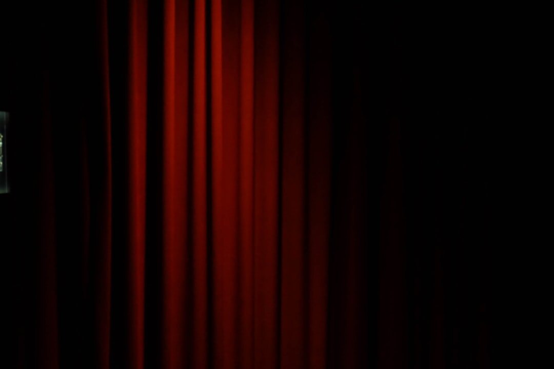 Empty vintage theater stage with red curtains and a single spotlight
